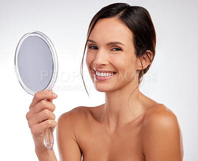 Buy stock photo Shot of an attractive young woman holding a hand mirror and posing in the studio