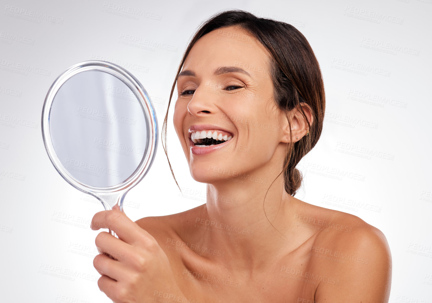 Buy stock photo Shot of an attractive young woman holding a hand mirror and posing in the studio