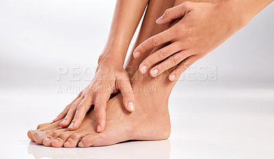 Buy stock photo Cropped shot of an unrecognizable woman touching her feet in the studio