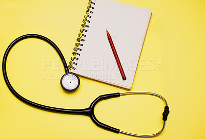 Buy stock photo Studio shot of a stethoscope and a notebook against a yellow background