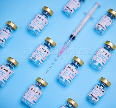 Buy stock photo Shot of vaccines and a syringe against a blue background