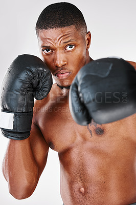 Buy stock photo Studio portrait of a young shirtless man posing with boxing gloves against a white background