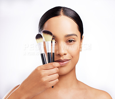Buy stock photo Studio portrait of a beautiful young woman holding a collection of makeup brushes against a white background