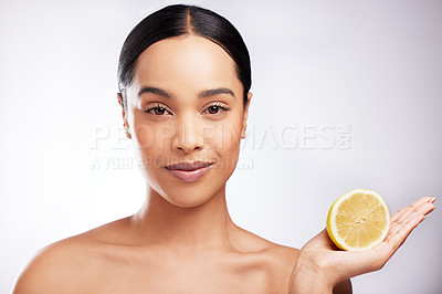 Buy stock photo Studio portrait of a beautiful young woman posing with a lemon against a white background