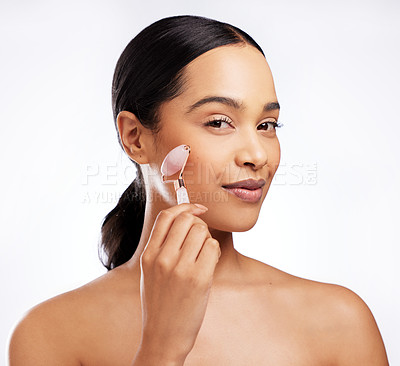 Buy stock photo Studio portrait of a beautiful young woman using a jade roller on her face against a white background