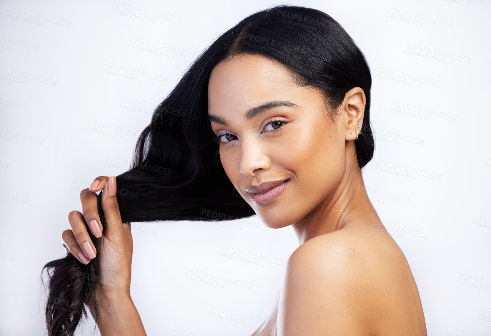 Buy stock photo Shot of an attractive young woman standing alone in the studio and holding her hair