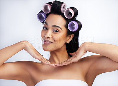 Buy stock photo Shot of an attractive young woman standing alone in the studio and using rollers in her hair