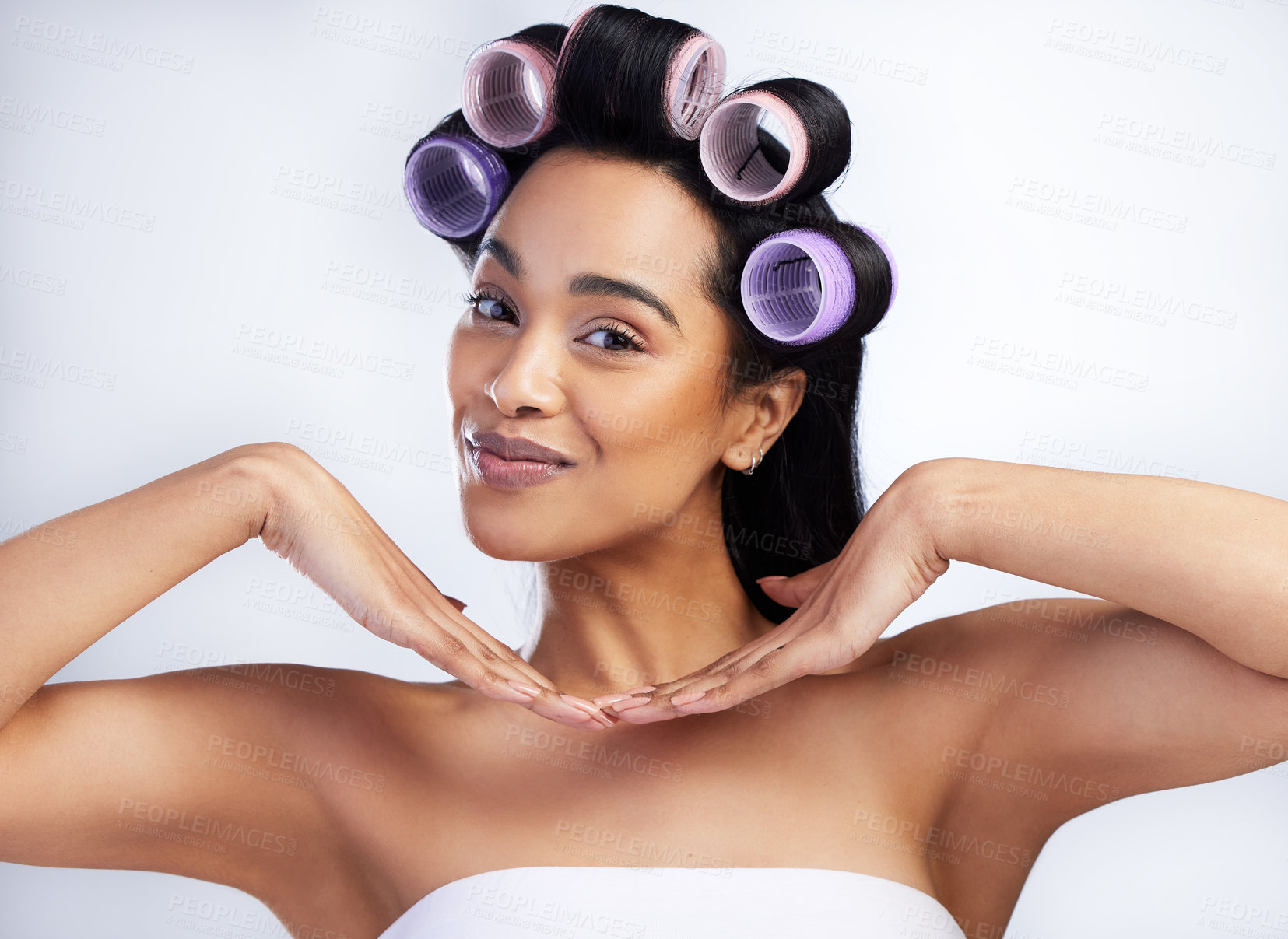 Buy stock photo Shot of an attractive young woman standing alone in the studio and using rollers in her hair