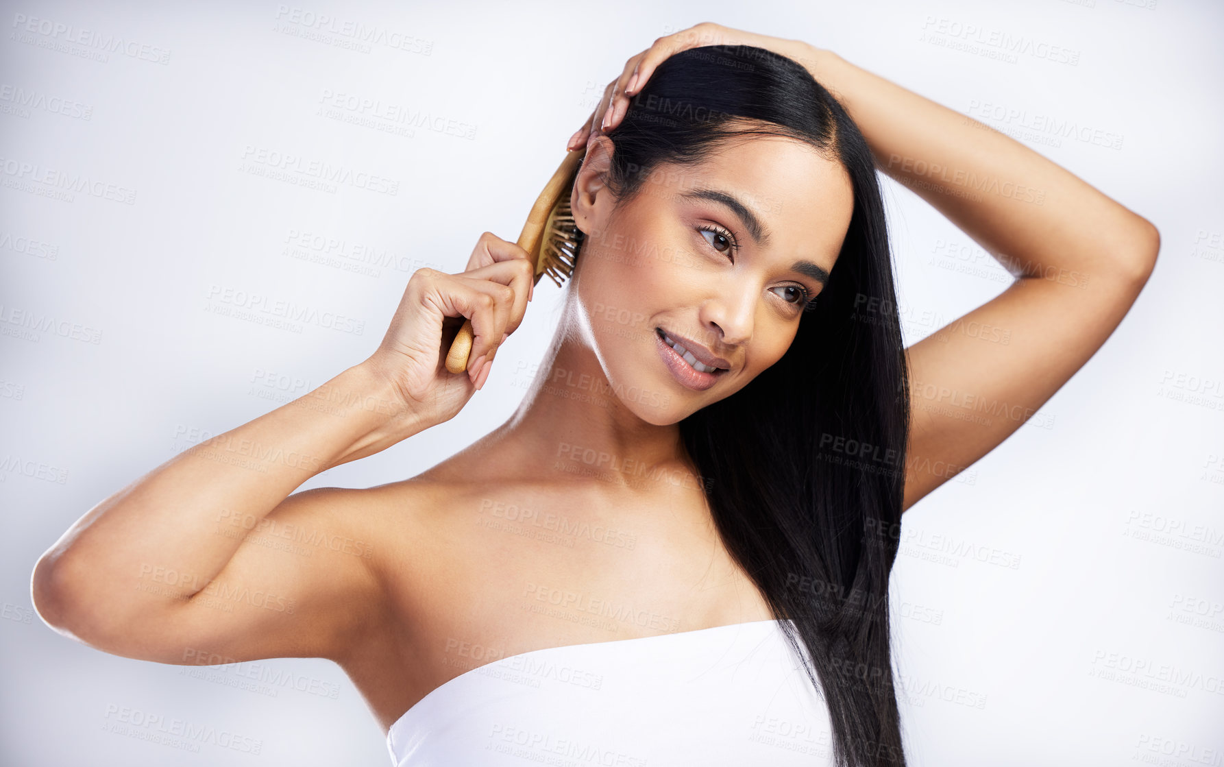 Buy stock photo Shot of an attractive young woman standing alone in the studio and brushing her hair