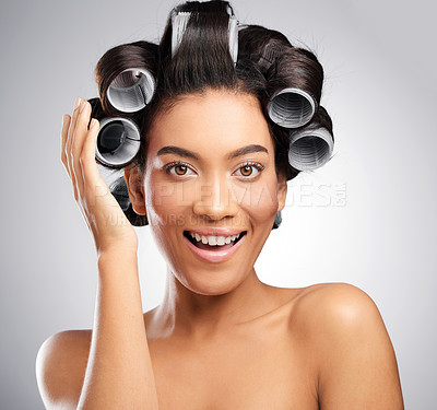 Buy stock photo Studio shot of an attractive young woman posing with curlers in her hair against a grey background