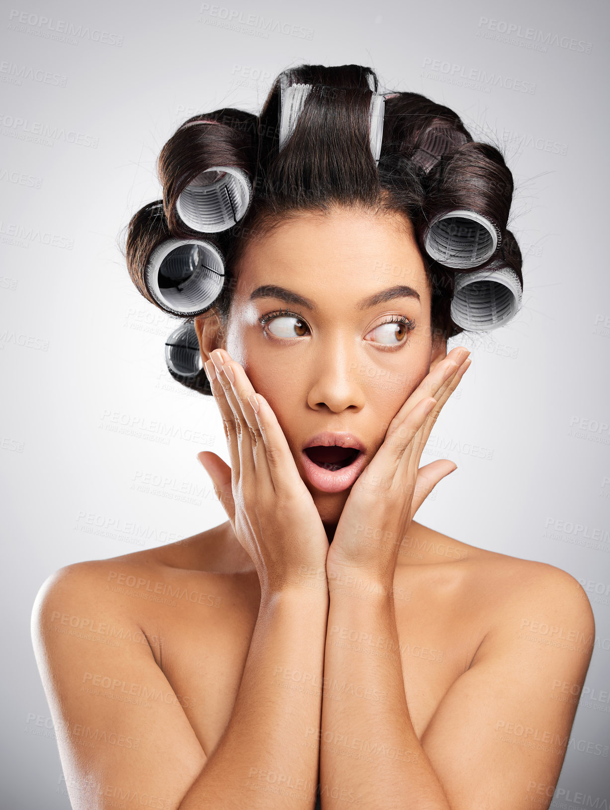 Buy stock photo Studio shot of an attractive young woman posing with curlers in her hair against a grey background