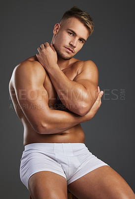 Buy stock photo Cropped portrait of a handsome and athletic young man posing shirtless in studio against a dark background