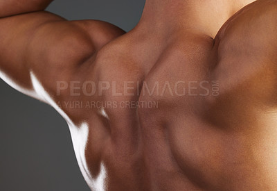 Buy stock photo Closeup shot of an unrecognizable and athletic young man's back while he poses shirtless in studio against a dark background