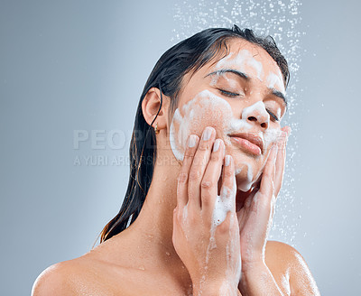 Buy stock photo Shot of a young woman washing her face in the shower against a grey background