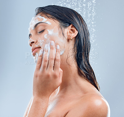 Buy stock photo Shot of a young woman washing her face in the shower against a grey background