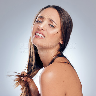 Buy stock photo Shot of an attractive young woman standing alone in the studio and looking upset while holding her hair