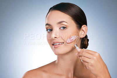 Buy stock photo Portrait, woman and skincare for beauty with face roller, satisfied and results for glowing skin in blue background. Female person, studio and cosmetic product with pride, dermatology for wellness