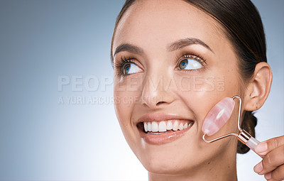 Buy stock photo Shot of an attractive young woman using a derma roller against against a blue background