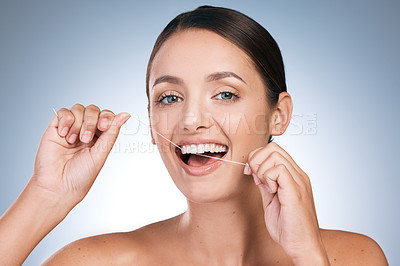 Buy stock photo Woman, portrait and flossing in studio, orthodontics and cosmetics for smile on blue background. Female person, dental health and string for grooming teeth, cleaning and self care or whitening