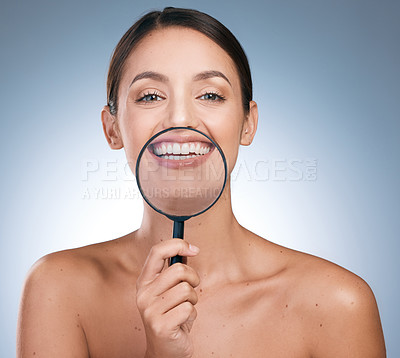 Buy stock photo Portrait of a a young beautiful woman having fun with a magnifying glass against a blue background