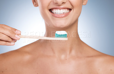 Buy stock photo Cropped shot of a young woman brushing her teeth against a blue background