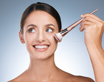 Buy stock photo Shot of a young attractive woman applying makeup against a blue background