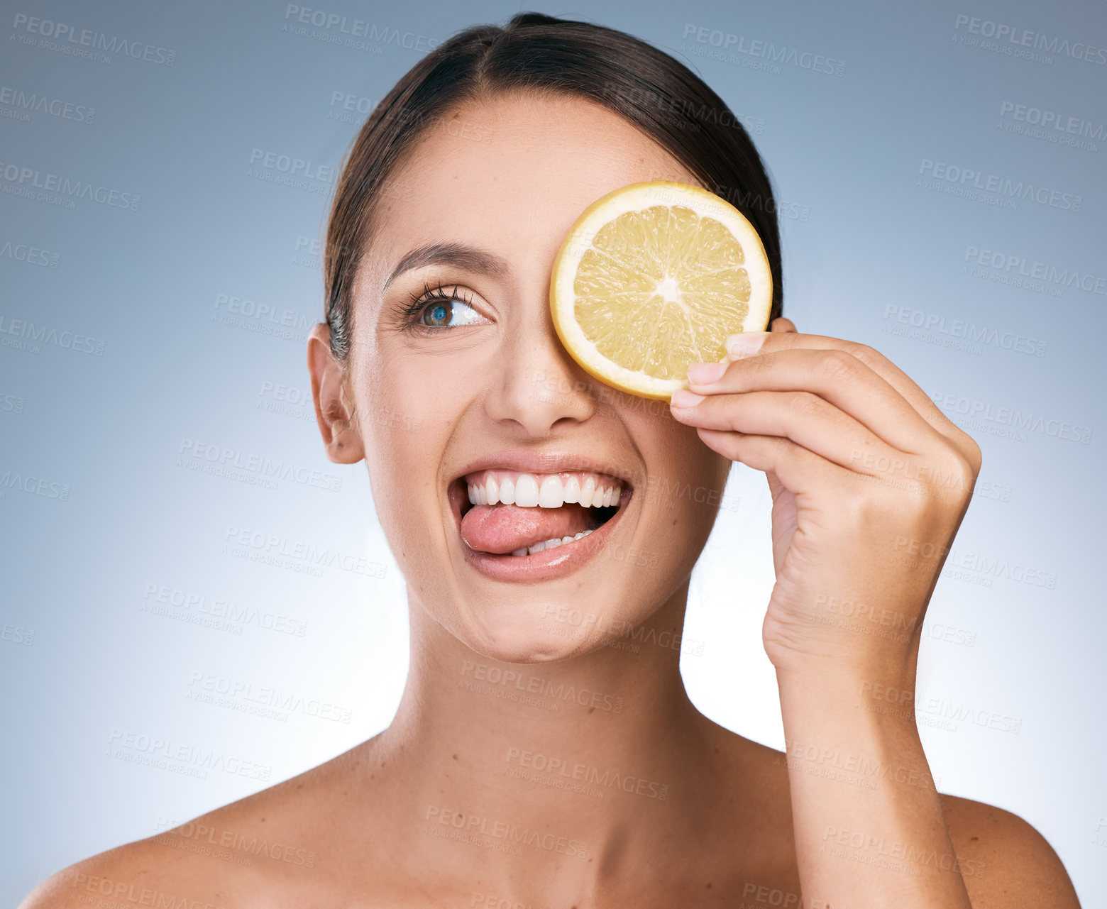 Buy stock photo Shot of an attractive young woman posing with a sliced orange against a blue background