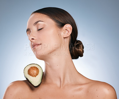 Buy stock photo Shot of an attractive young woman posing with a sliced avocado on her shoulder  against a blue background