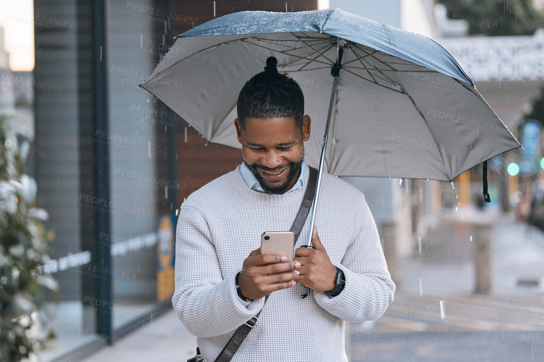 Buy stock photo Rain, walking and black man in city with phone, text message and travel to work in London. Outdoor, business person and umbrella for protection, winter weather and mobile app for chat in social media