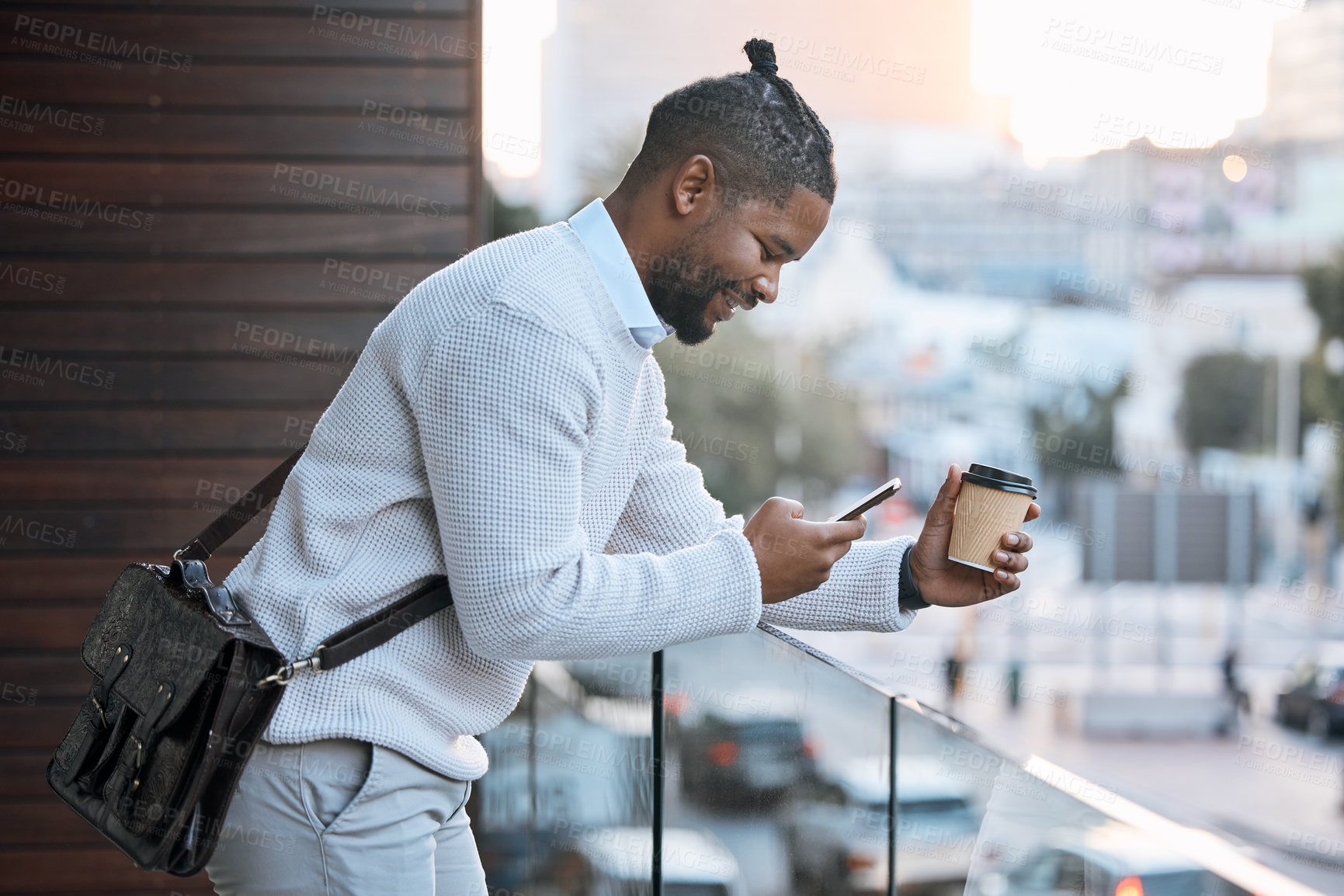 Buy stock photo Cropped shot of a handsome young businessman texting while enjoying a takeaway coffee outside on the office balcony