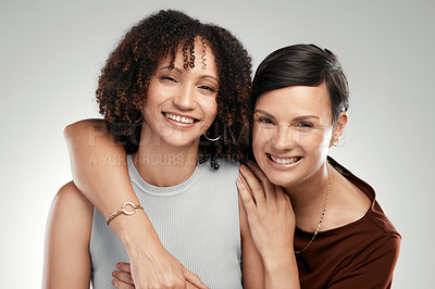 Buy stock photo Shot of two attractive women standing close together in the studio