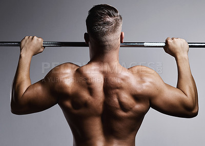Buy stock photo Studio shot of a muscular young man doing pull ups against a grey background