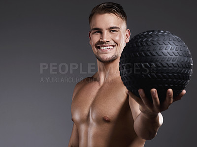 Buy stock photo Shot of a sporty young man holding an exercise ball while standing against a grey background