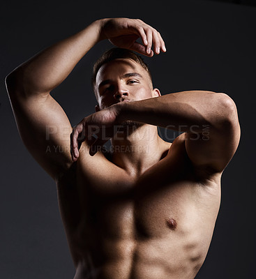 Buy stock photo Shot of a muscular young man posing against a black background
