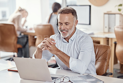 Buy stock photo Shot of a mature man using a headset and laptop in a modern office