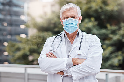 Buy stock photo Shot of a mature male doctor standing with his arms crossed in the city