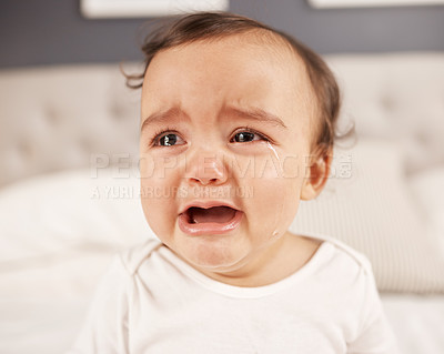 Buy stock photo Shot of an adorable little girl crying while sitting on a bed