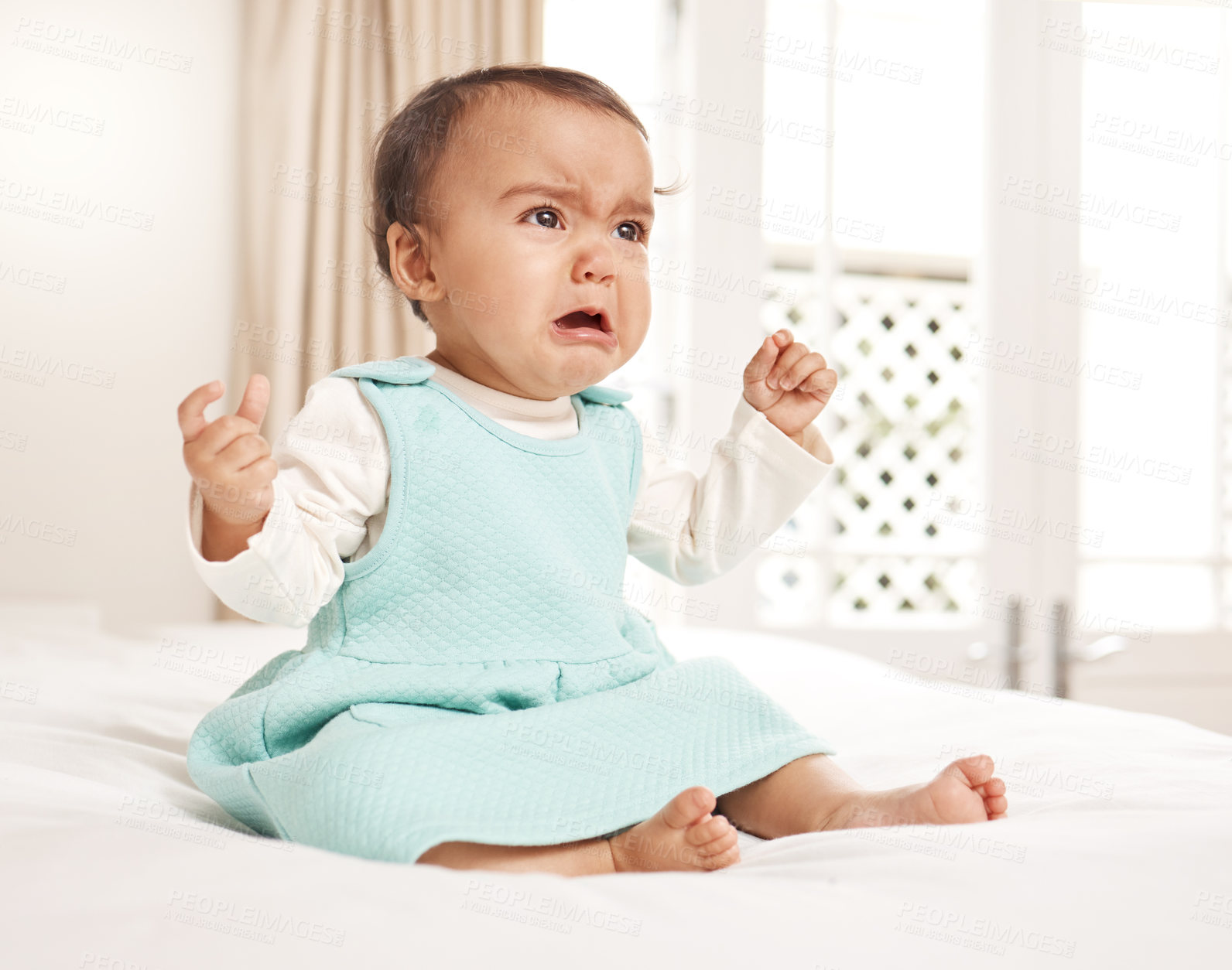 Buy stock photo Shot of an adorable little girl crying while sitting on a bed