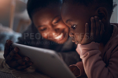 Buy stock photo Shot of a mother reading bedtime stories with her daughter on a digital tablet