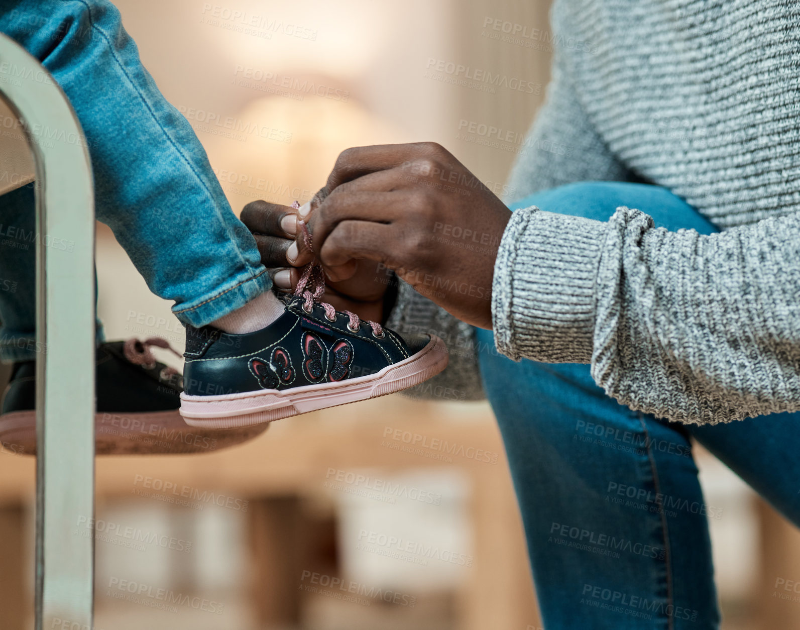 Buy stock photo Cropped shot of an unrecognizable man helping his daughter tie her shoelaces in the living room at home