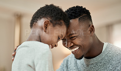 Buy stock photo Cropped shot of a handsome young man and his son standing face to face with their heads touching in the living room at home