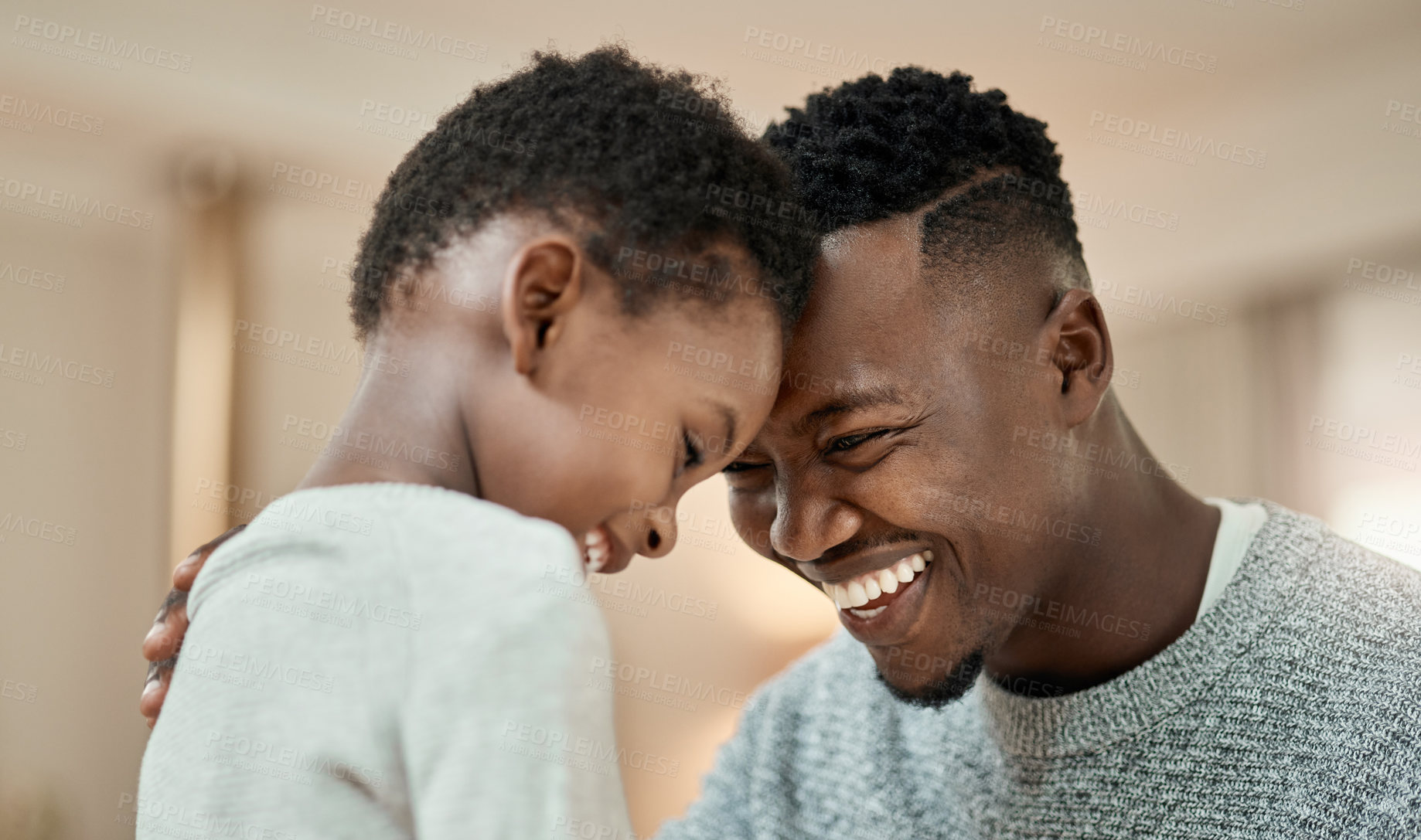 Buy stock photo Cropped shot of a handsome young man and his son standing face to face with their heads touching in the living room at home