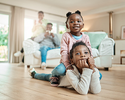 Buy stock photo Full length shot of an adorable little girl sitting on her brother's back on the living room floor at home