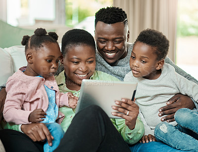Buy stock photo Cropped shot of an affectionate young family of four using a tablet while sitting on a sofa in their living room at home