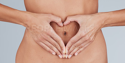 Buy stock photo Cropped shot of an unrecognizable woman standing alone in the studio and making a heart-shaped gesture over her tummy