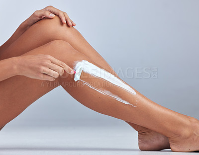 Buy stock photo Cropped shot of an unrecognizable woman sitting alone and shaving her legs in the studio