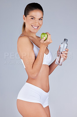 Buy stock photo Portrait, woman and apple with water bottle for healthy diet, fitness and nutrition in grey studio background. Wellness, female person and fruit with drink for organic meal, snack or vegan eating