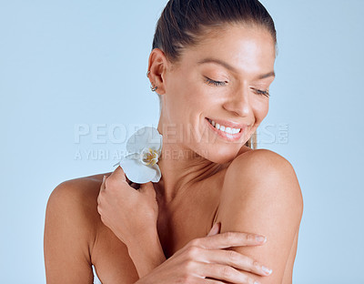 Buy stock photo Shot of an attractive young woman standing alone and posing in the studio while holding an orchid