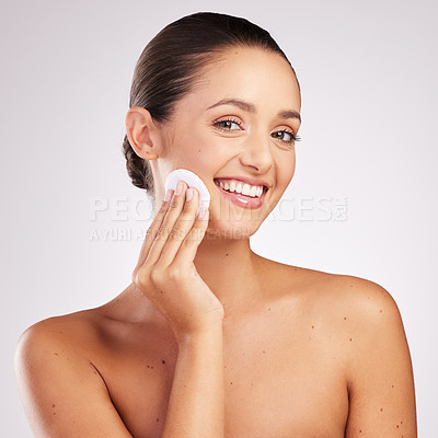 Buy stock photo Shot of an attractive young woman wiping her face with cotton against a studio background