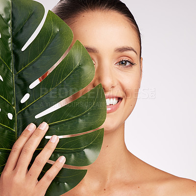 Buy stock photo Shot of an attractive young woman standing behind a plant against a studio background